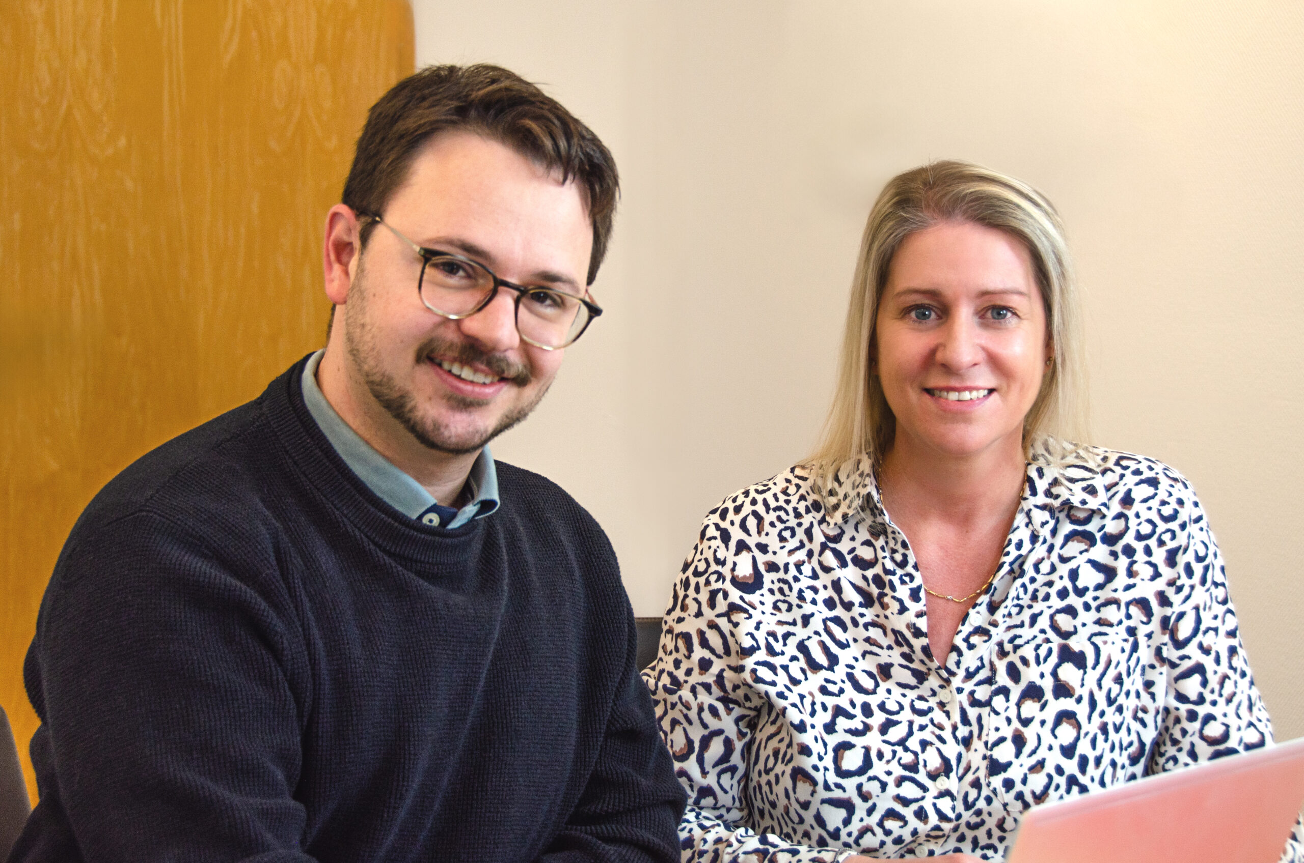 Eine junge Frau und ein junger Mann schauen freundlich in die Kamera